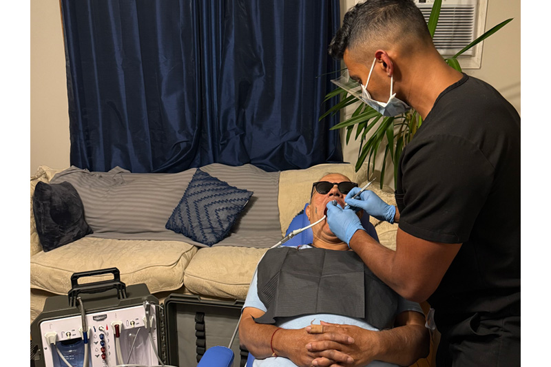 Dr. Nath providing in-home dental care to a patient on Long Island with portable dental equipment
